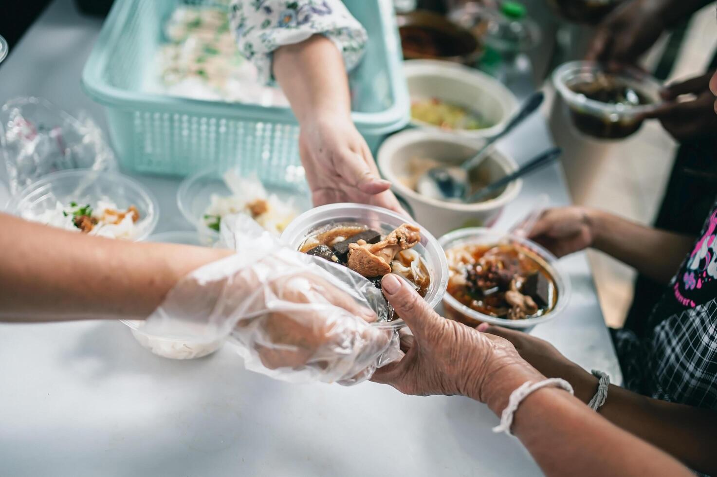 Feeding Concepts . Hand offered to donate food from a rich man Share. The concept of social sharing . Poor people receiving food from donations photo