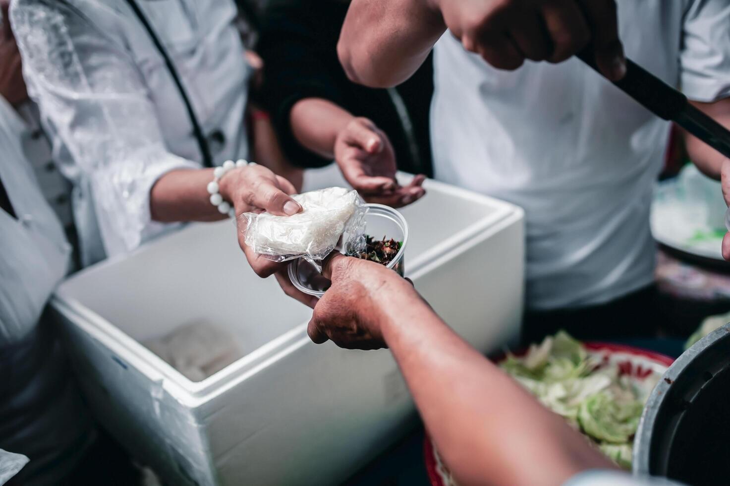 Feeding Concepts . Hand offered to donate food from a rich man Share. The concept of social sharing . Poor people receiving food from donations photo