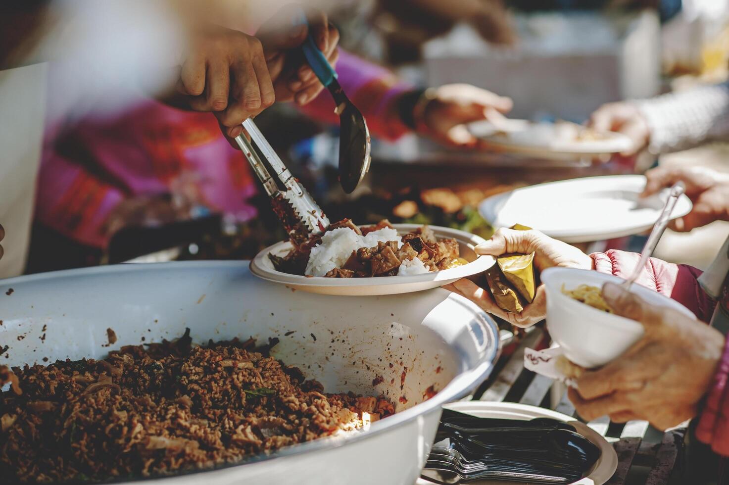 Feeding concept Homeless people offer free food from outdoor volunteers. photo