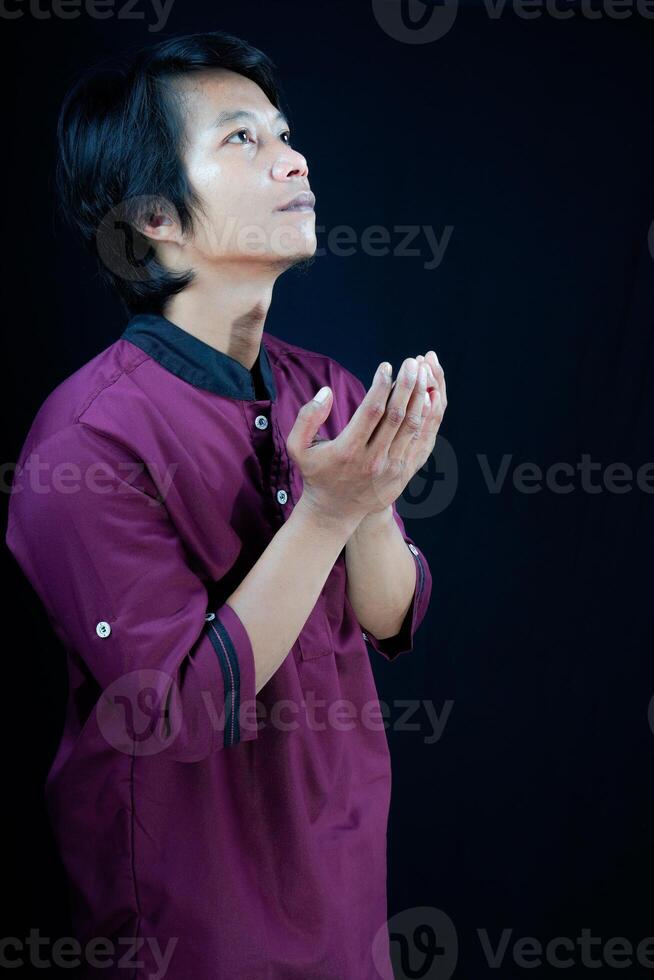 side view of a man raising his hands in prayer on a black background. photo