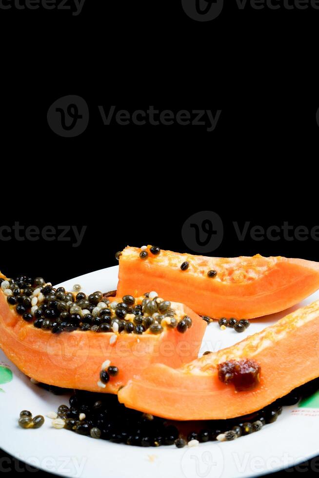 close up view of papaya fruit isolated on plate on black background. photo