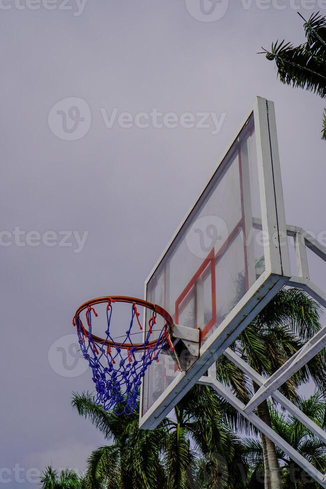 Close-up view of a basketball basket against a cloudy sky background. photo