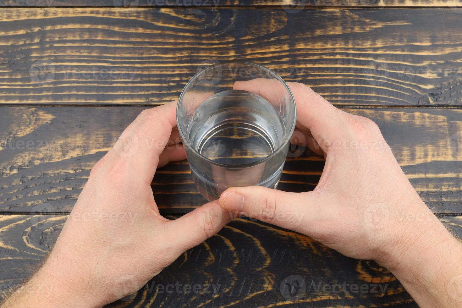 A glass of water in hands on the table photo