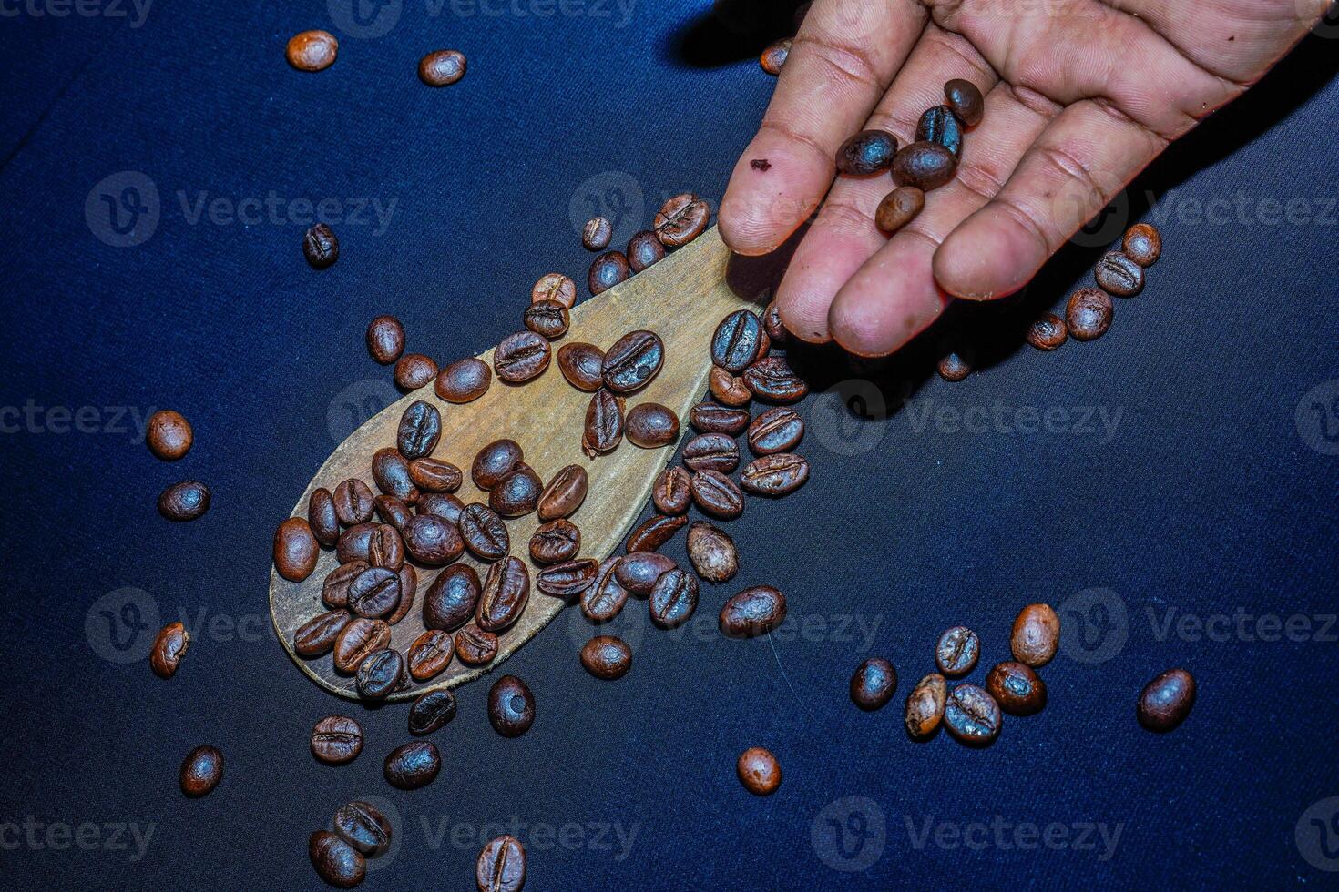 negro café frijoles son visto cerca arriba con un de madera cuchara en un negro paño. foto