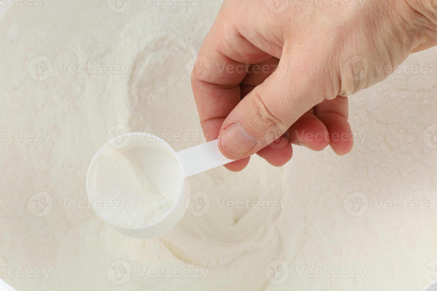 The hand scoops the gainer into the jar photo