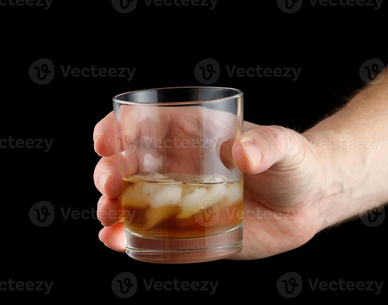 Whiskey with ice in a glass in hand. photo