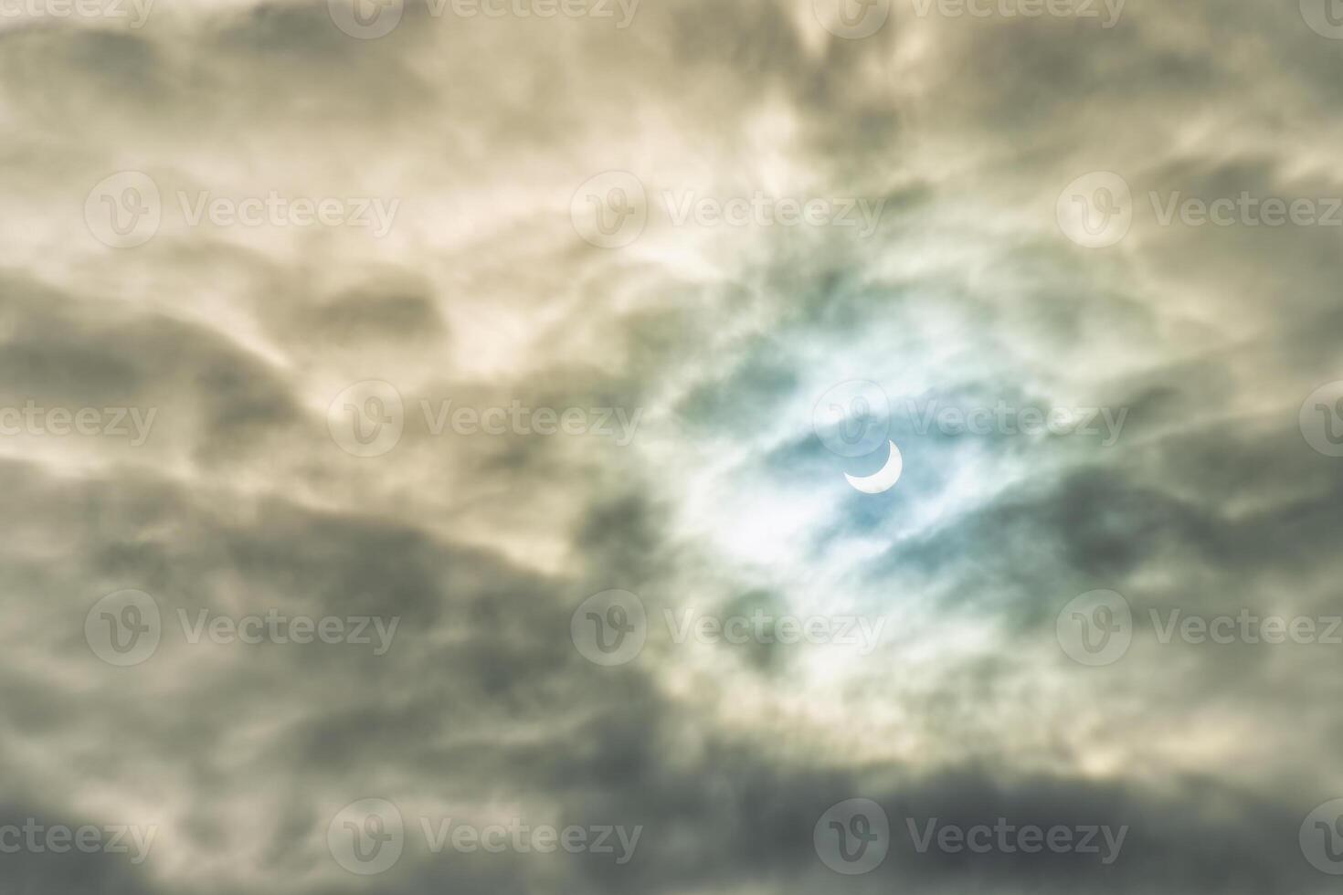 Partial solar eclipse passing behind the clouds. photo