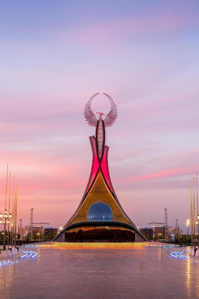 UZBEKISTAN, TASHKENT - SEPTEMBER 15, 2023 Monument of Independence in the form of a stele with a Humo bird on a twilight with dramatic cliods in the New Uzbekistan park. photo