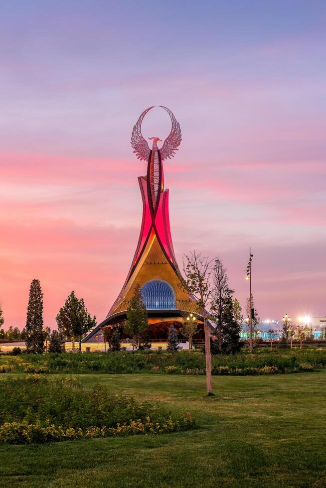 UZBEKISTAN, TASHKENT - SEPTEMBER 15, 2023 Monument of Independence in the form of a stele with a Humo bird on a twilight with dramatic cliods in the New Uzbekistan park. photo
