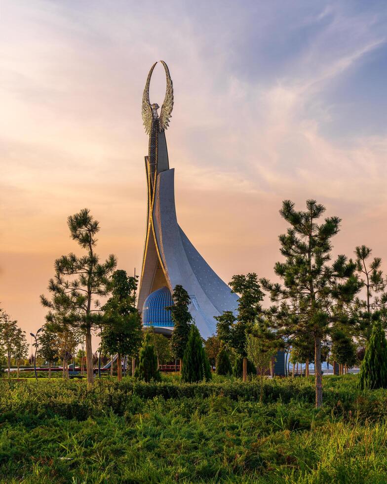 UZBEKISTAN, TASHKENT - SEPTEMBER 15, 2023 Monument of Independence in the form of a stele with a Humo bird on a twilight with dramatic cliods in the New Uzbekistan park. photo