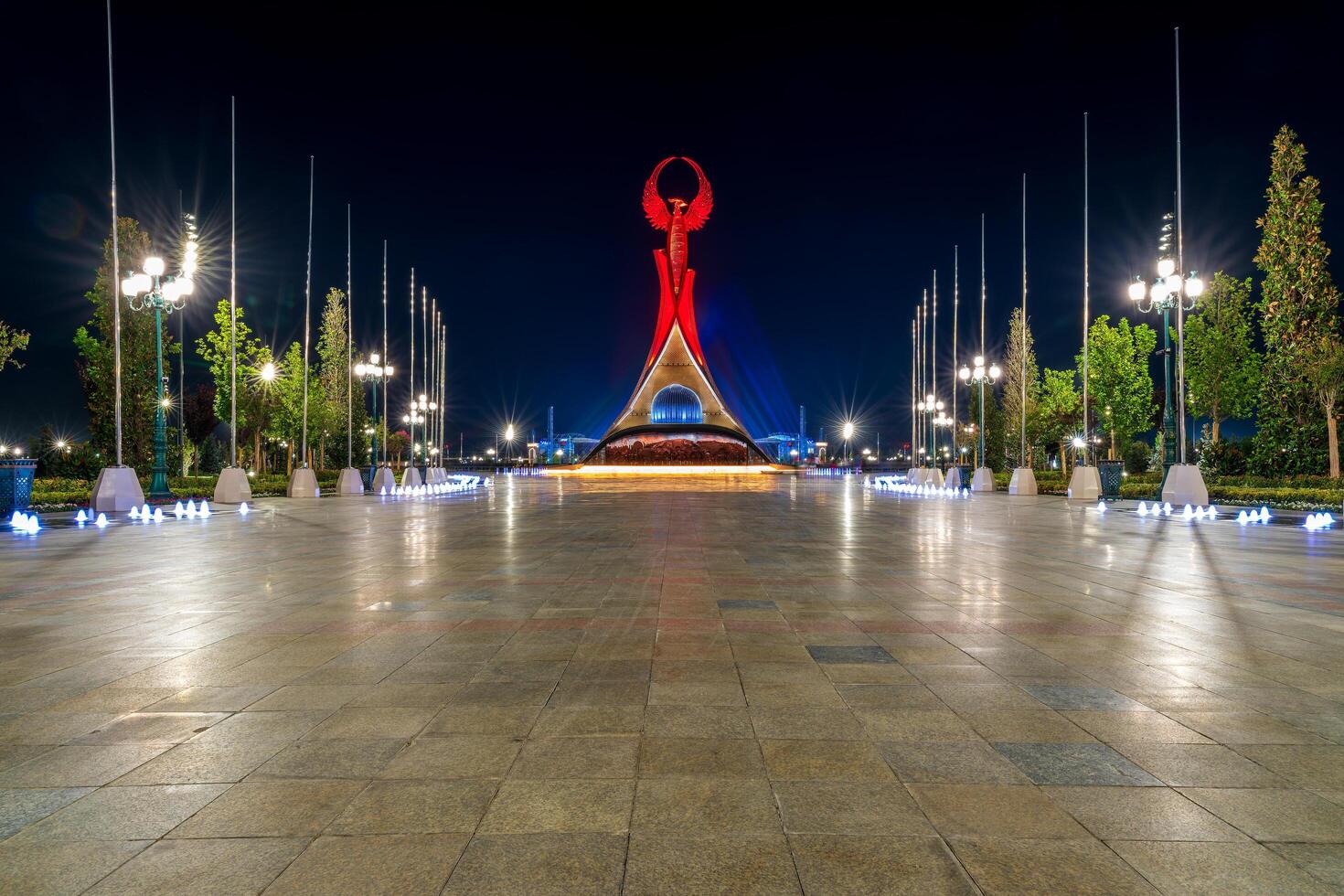UZBEKISTAN, TASHKENT - SEPTEMBER 15, 2023 Illuminated monument of independence in the form of a stele with a Humo bird in the New Uzbekistan park at nighttime in autumn. photo