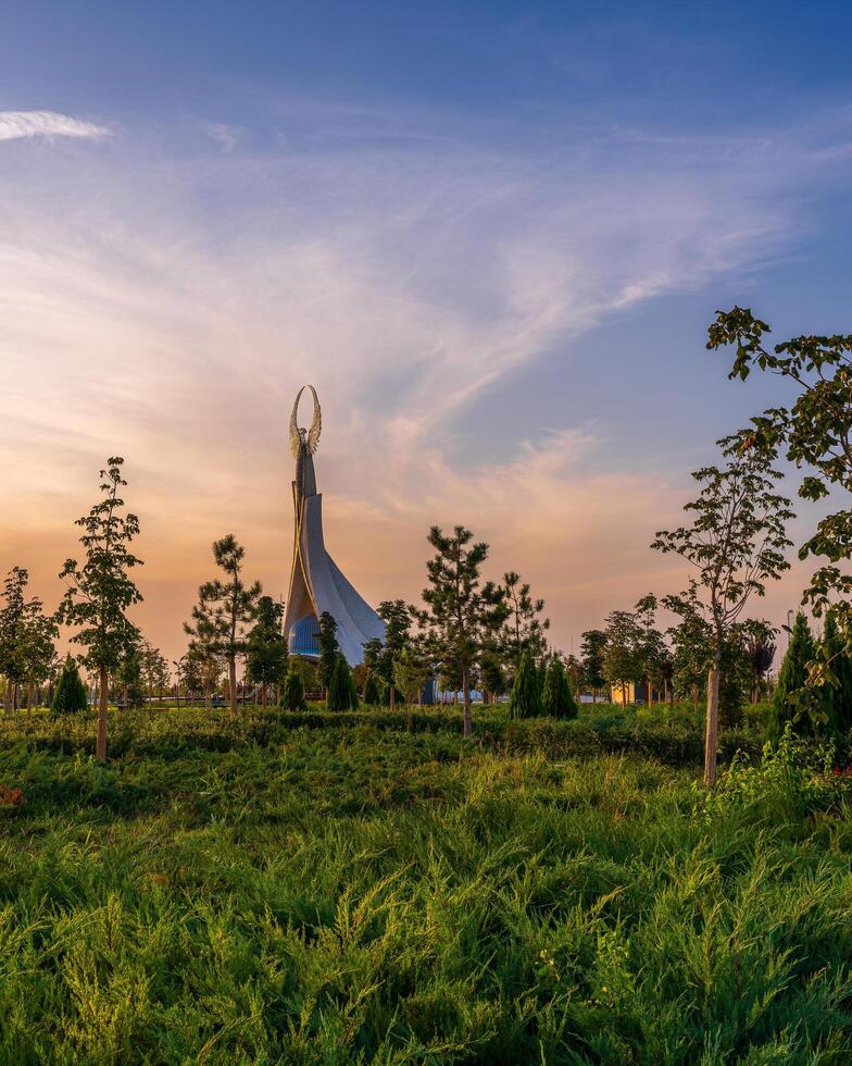 UZBEKISTAN, TASHKENT - SEPTEMBER 15, 2023 Monument of Independence in the form of a stele with a Humo bird on a twilight with dramatic cliods in the New Uzbekistan park. photo