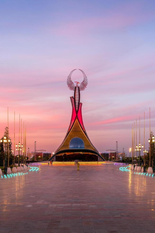 UZBEKISTAN, TASHKENT - SEPTEMBER 15, 2023 Monument of Independence in the form of a stele with a Humo bird on a twilight with dramatic cliods in the New Uzbekistan park. photo