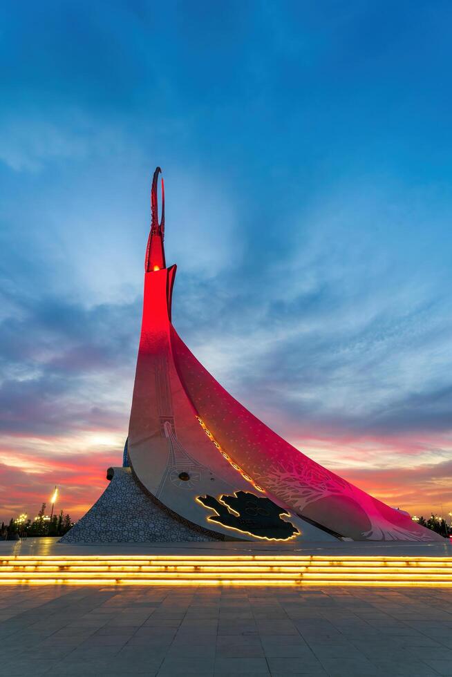 UZBEKISTAN, TASHKENT - SEPTEMBER 15, 2023 Monument of Independence in the form of a stele with a Humo bird on a twilight with dramatic cliods in the New Uzbekistan park. photo