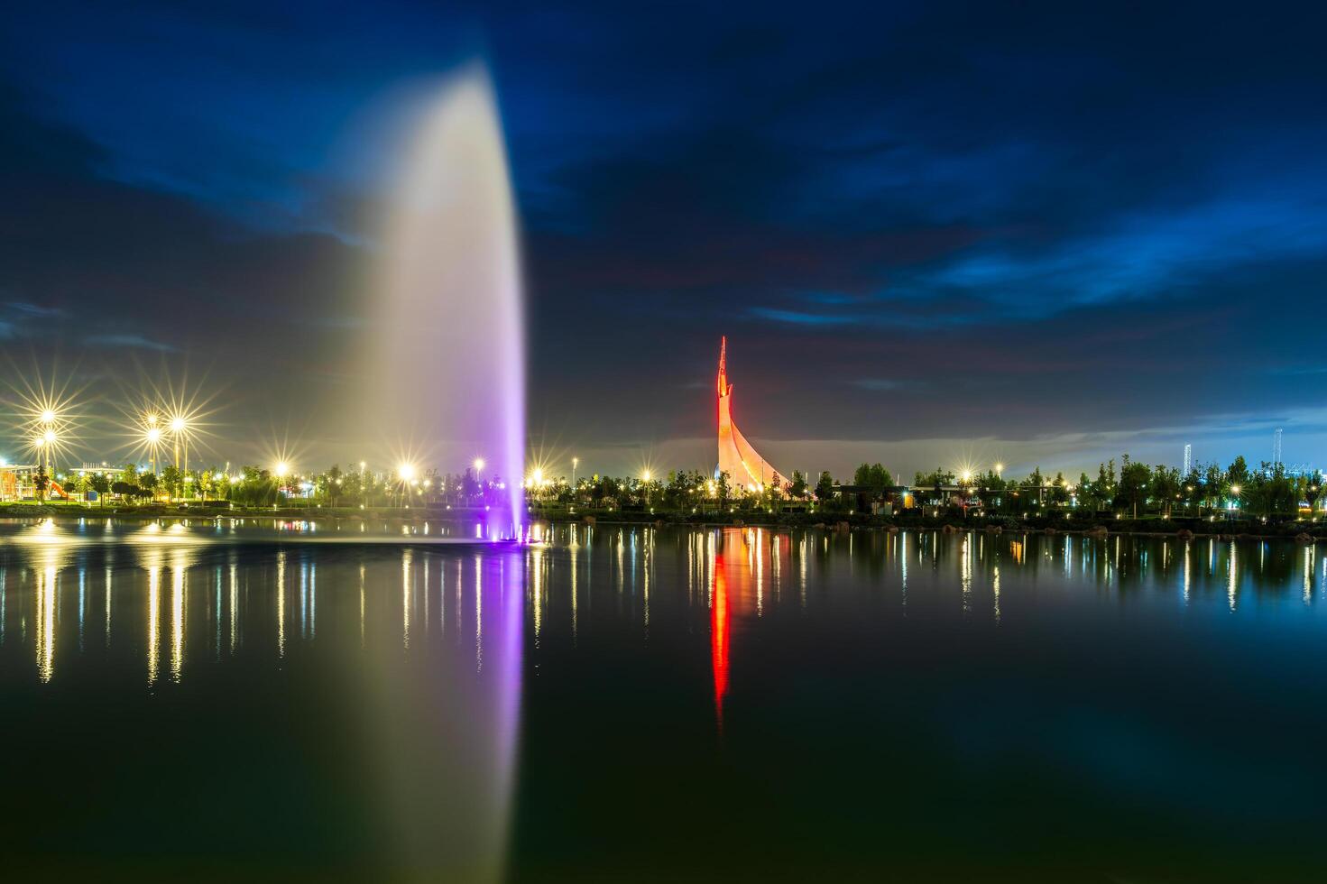 UZBEKISTAN, TASHKENT - SEPTEMBER 15, 2023 Illuminated monument of independence in the form of a stele with a Humo bird and fountain in the New Uzbekistan park at nighttime in autumn. photo