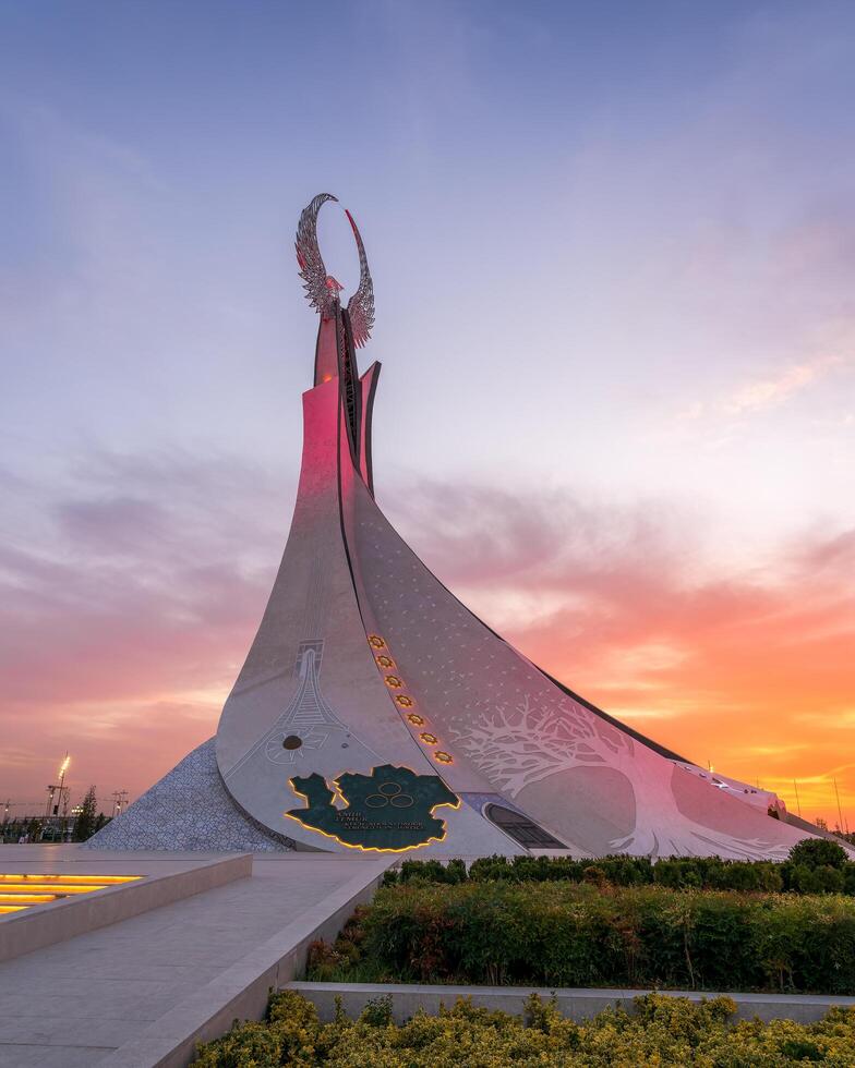 UZBEKISTAN, TASHKENT - SEPTEMBER 15, 2023 Monument of Independence in the form of a stele with a Humo bird on a twilight with dramatic cliods in the New Uzbekistan park. photo