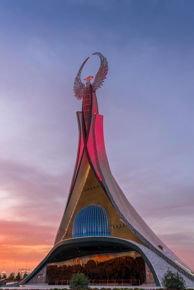 UZBEKISTAN, TASHKENT - SEPTEMBER 15, 2023 Monument of Independence in the form of a stele with a Humo bird on a twilight with dramatic cliods in the New Uzbekistan park. photo