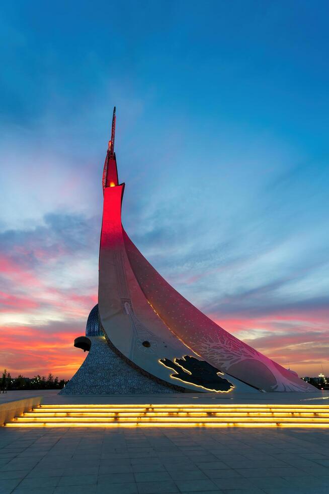 UZBEKISTAN, TASHKENT - SEPTEMBER 15, 2023 Monument of Independence in the form of a stele with a Humo bird on a twilight with dramatic cliods in the New Uzbekistan park. photo