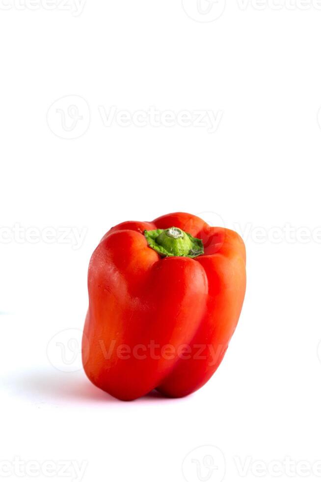 A vibrant red bell pepper sits on a clean white background. The pepper's glossy skin and bright color stand out, creating a striking contrast with the simple backdrop. photo