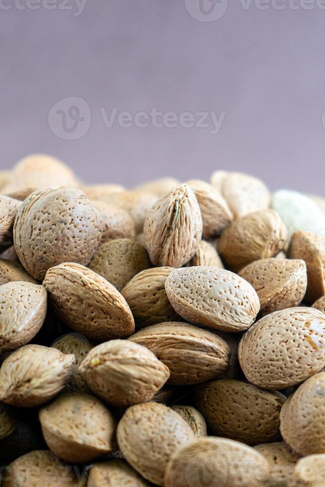 Pile of almonds in shells against a purple background. Vibrant composition capturing natural textures and colors. photo