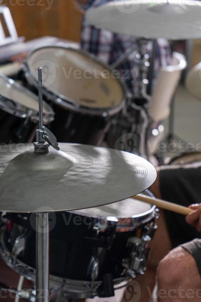 Close-up of a man's hands playing drums. His drumsticks hit with energy, showing the rhythm and motion of live performance. Cymbals and drumheads are slightly blurred, indicating movement. photo