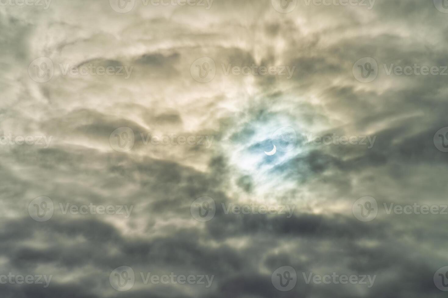 Partial solar eclipse passing behind the clouds. photo