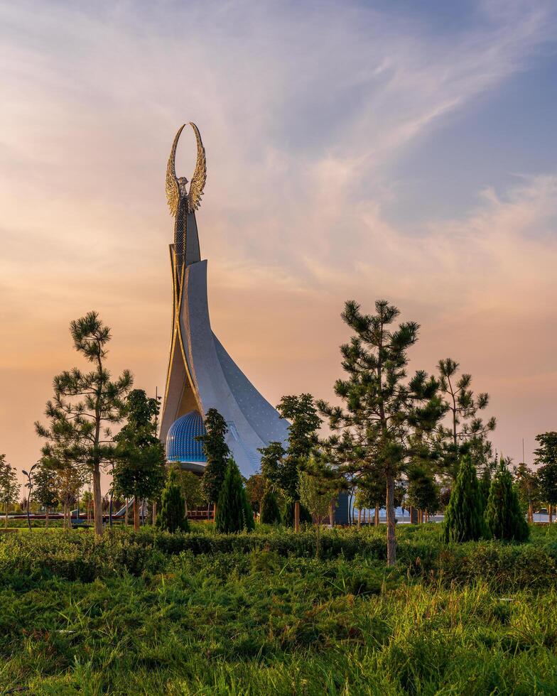 UZBEKISTAN, TASHKENT - SEPTEMBER 15, 2023 Monument of Independence in the form of a stele with a Humo bird on a twilight with dramatic cliods in the New Uzbekistan park. photo