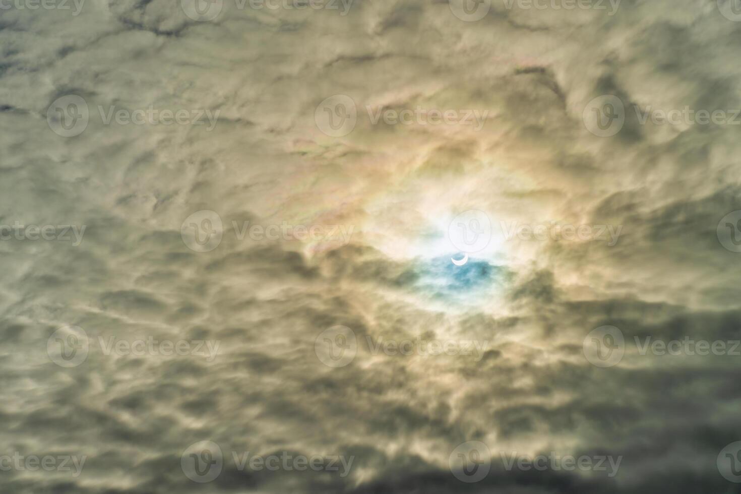 Partial solar eclipse passing behind the clouds. photo