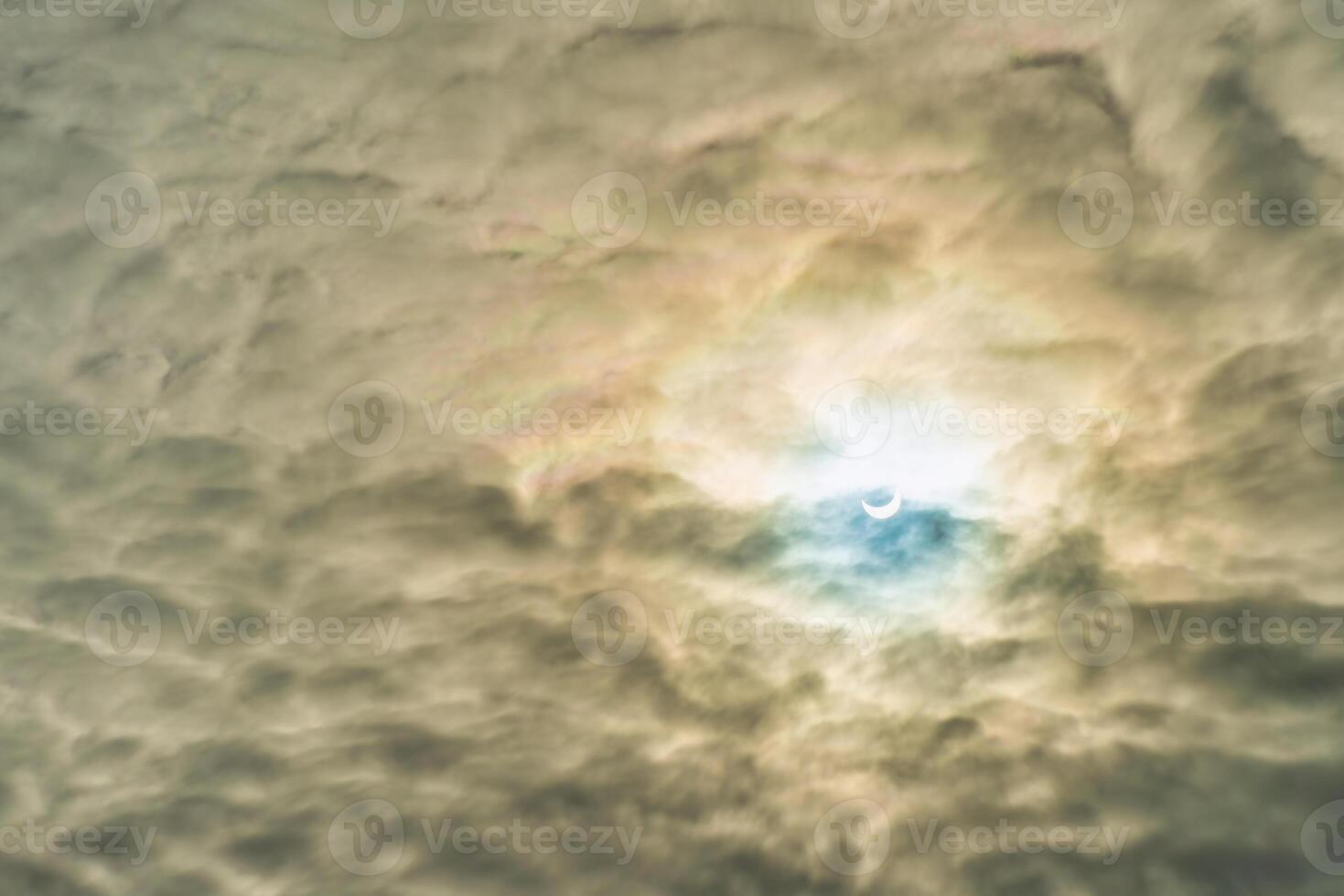 Partial solar eclipse passing behind the clouds. photo