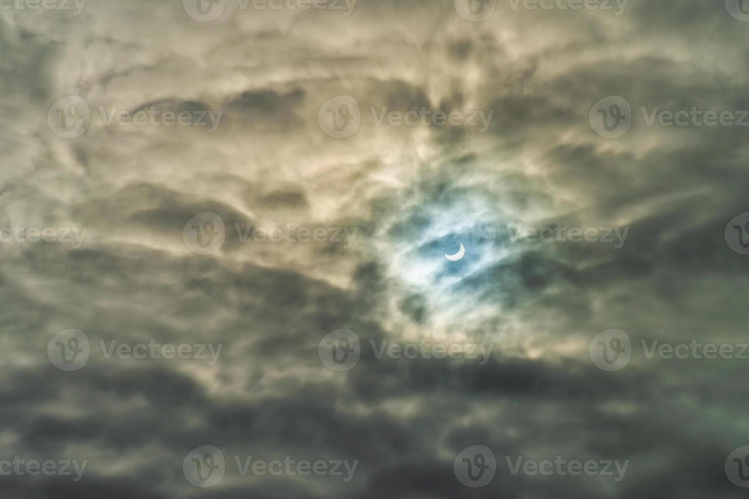 Partial solar eclipse passing behind the clouds. photo