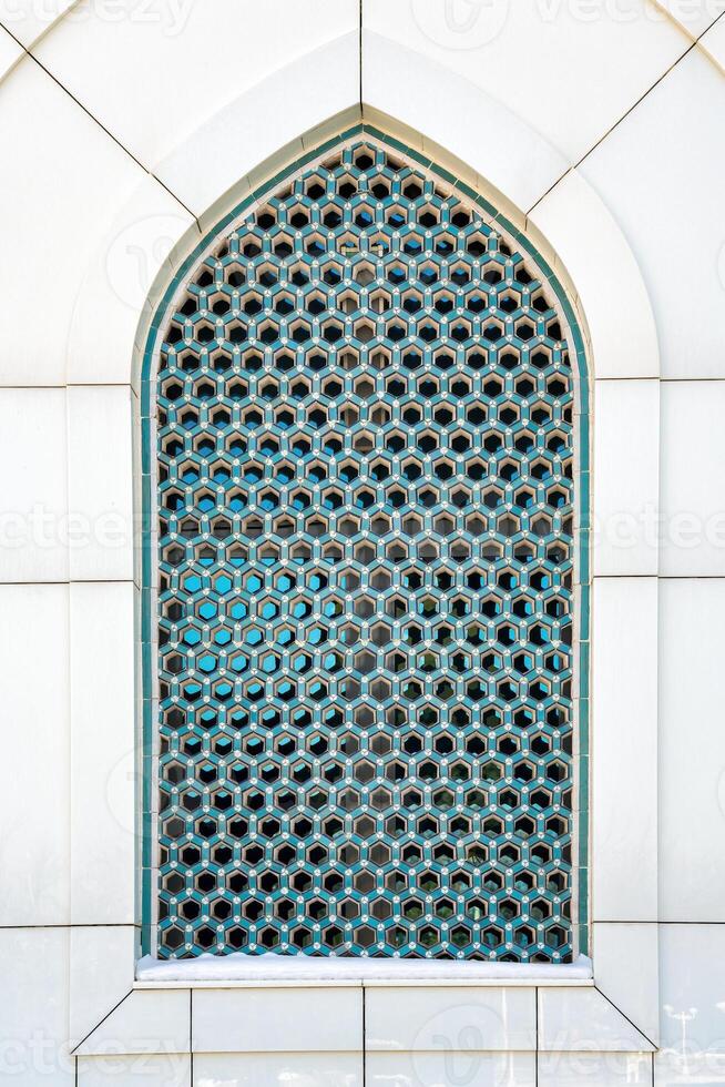 The window of a Muslim mosque behind bars in the form of a geometric hexagonal Islamic ornament. photo