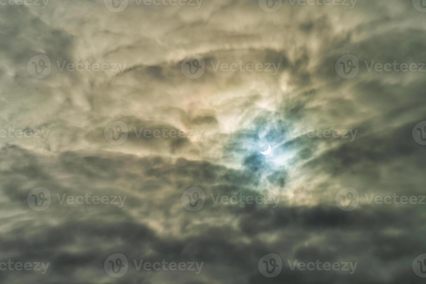 Partial solar eclipse passing behind the clouds. photo