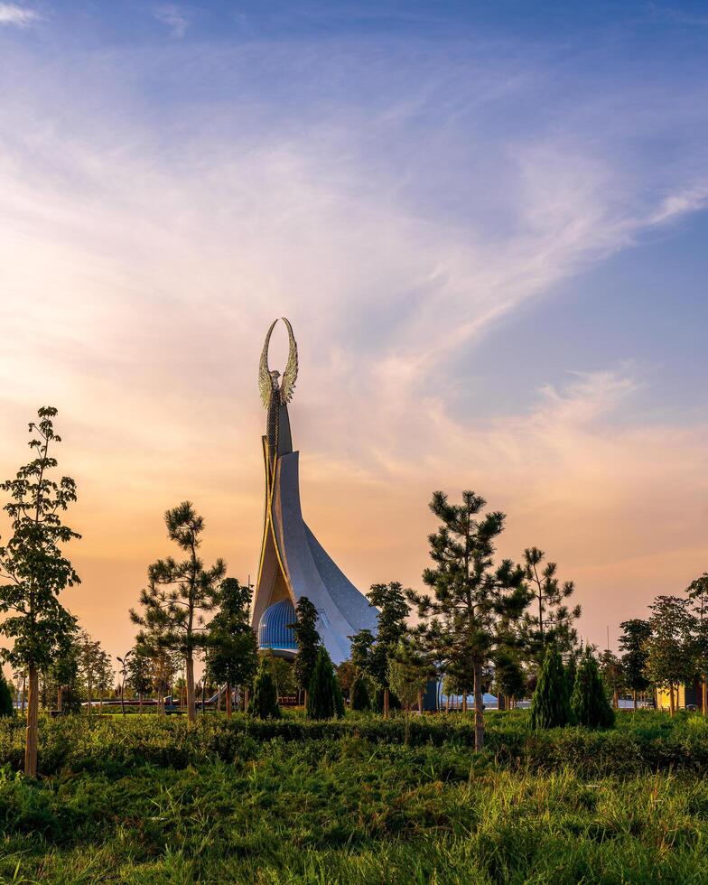 UZBEKISTAN, TASHKENT - SEPTEMBER 15, 2023 Monument of Independence in the form of a stele with a Humo bird on a twilight with dramatic cliods in the New Uzbekistan park. photo