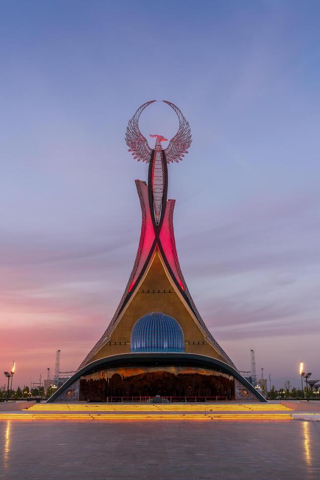 UZBEKISTAN, TASHKENT - SEPTEMBER 15, 2023 Monument of Independence in the form of a stele with a Humo bird on a twilight with dramatic cliods in the New Uzbekistan park. photo