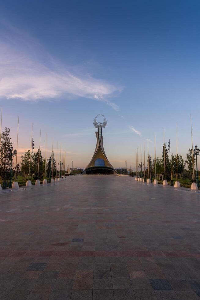 UZBEKISTAN, TASHKENT - SEPTEMBER 15, 2023 Monument of Independence in the form of a stele with a Humo bird on a twilight with dramatic cliods in the New Uzbekistan park. photo