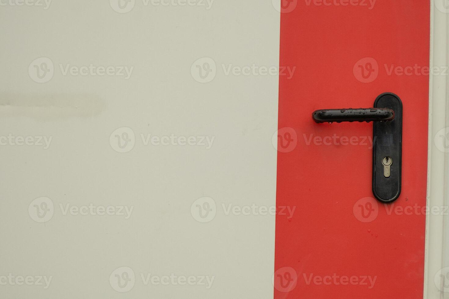 Black door handle against a white background with a wide red stripe photo