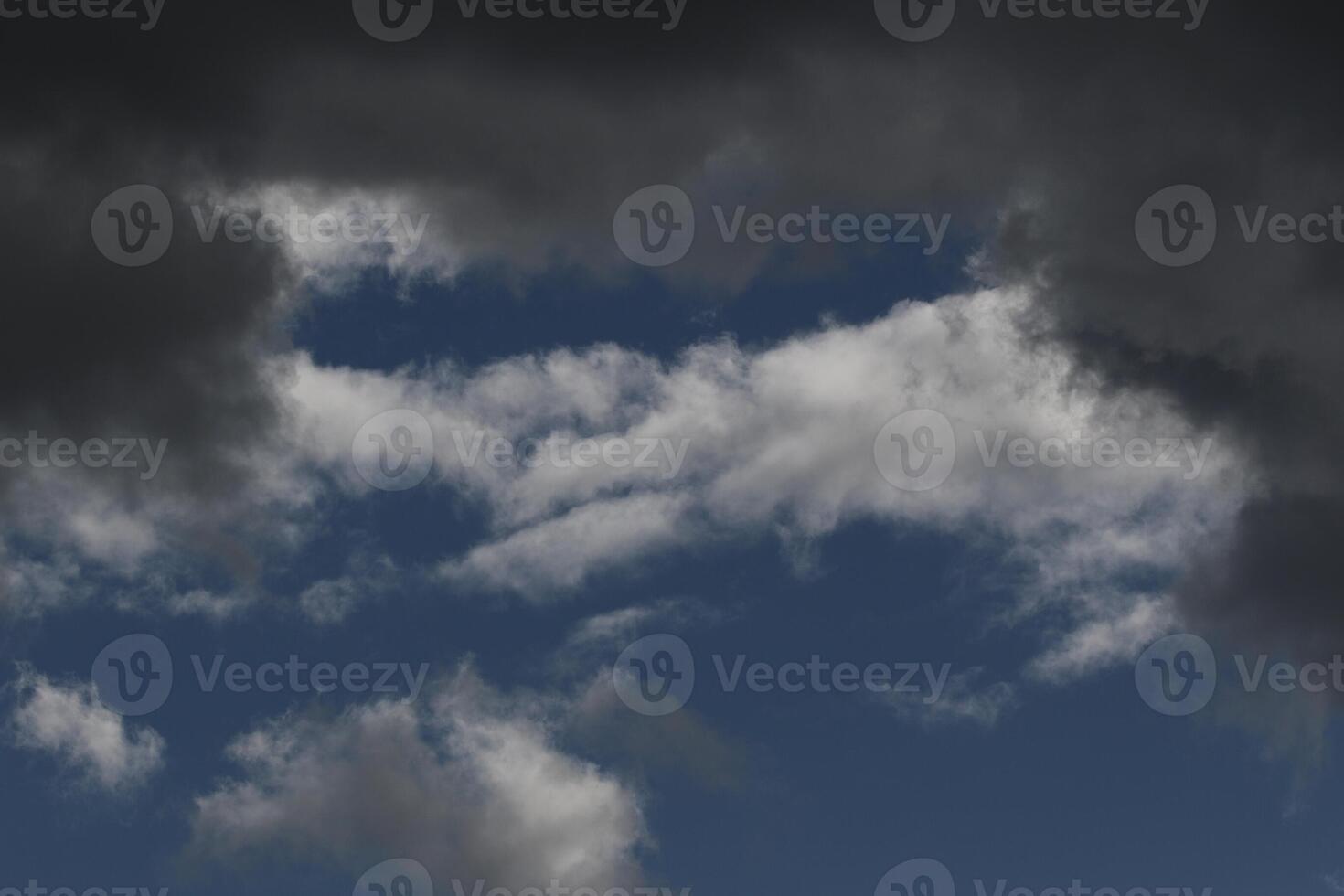 Cloudscape scenery, overcast weather above dark blue sky. Storm clouds floating in a rainy dull day with natural light. White and grey scenic environment background. Nature view. photo
