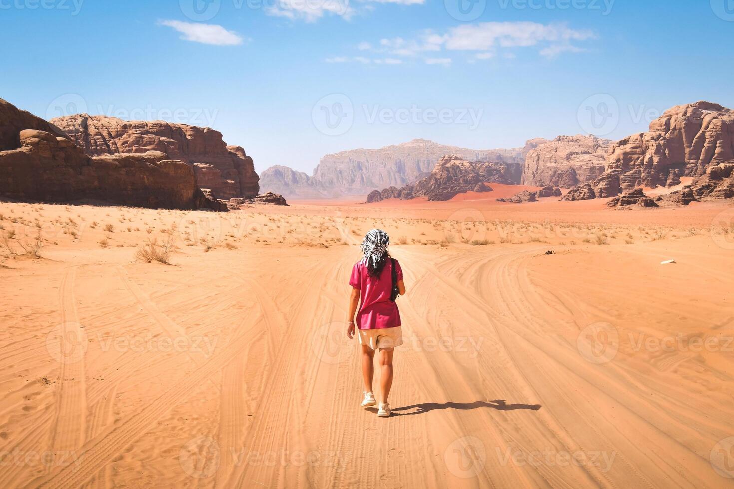 Adventure and explore in changed planet earth for climate warming concept - woman viewed from back walking on desert dunes with blue sky and wadi rum mars alike background photo