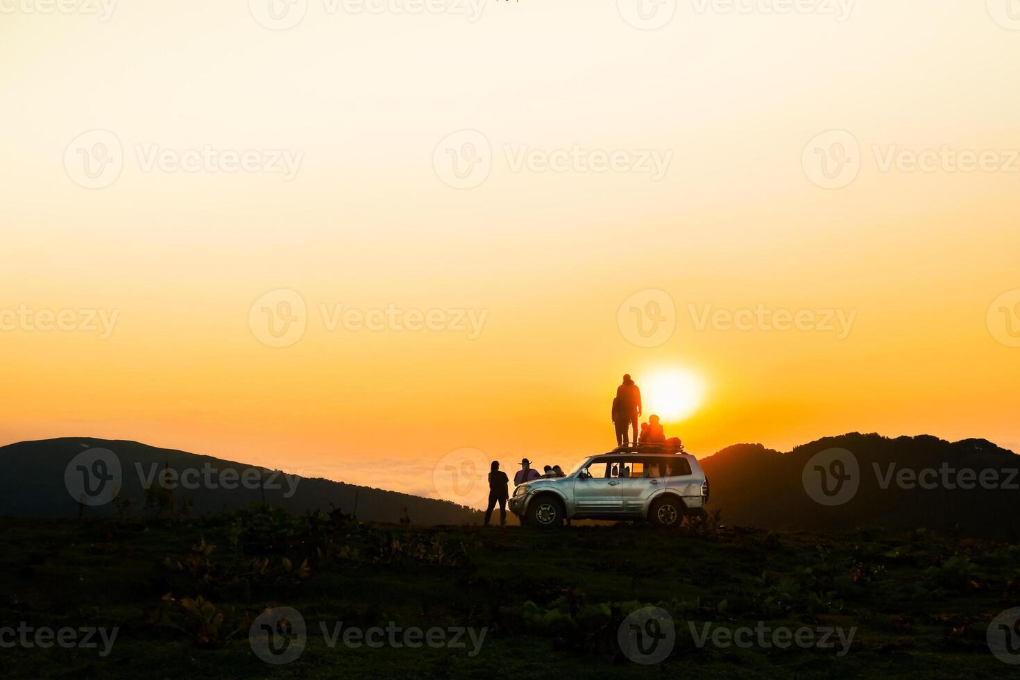 akhmaro, Georgia - 14th august, 2022 - Static view friends tour group stand on 4wd rooftop watch sunset together outdoors have fun above clouds in famous travel destination photo