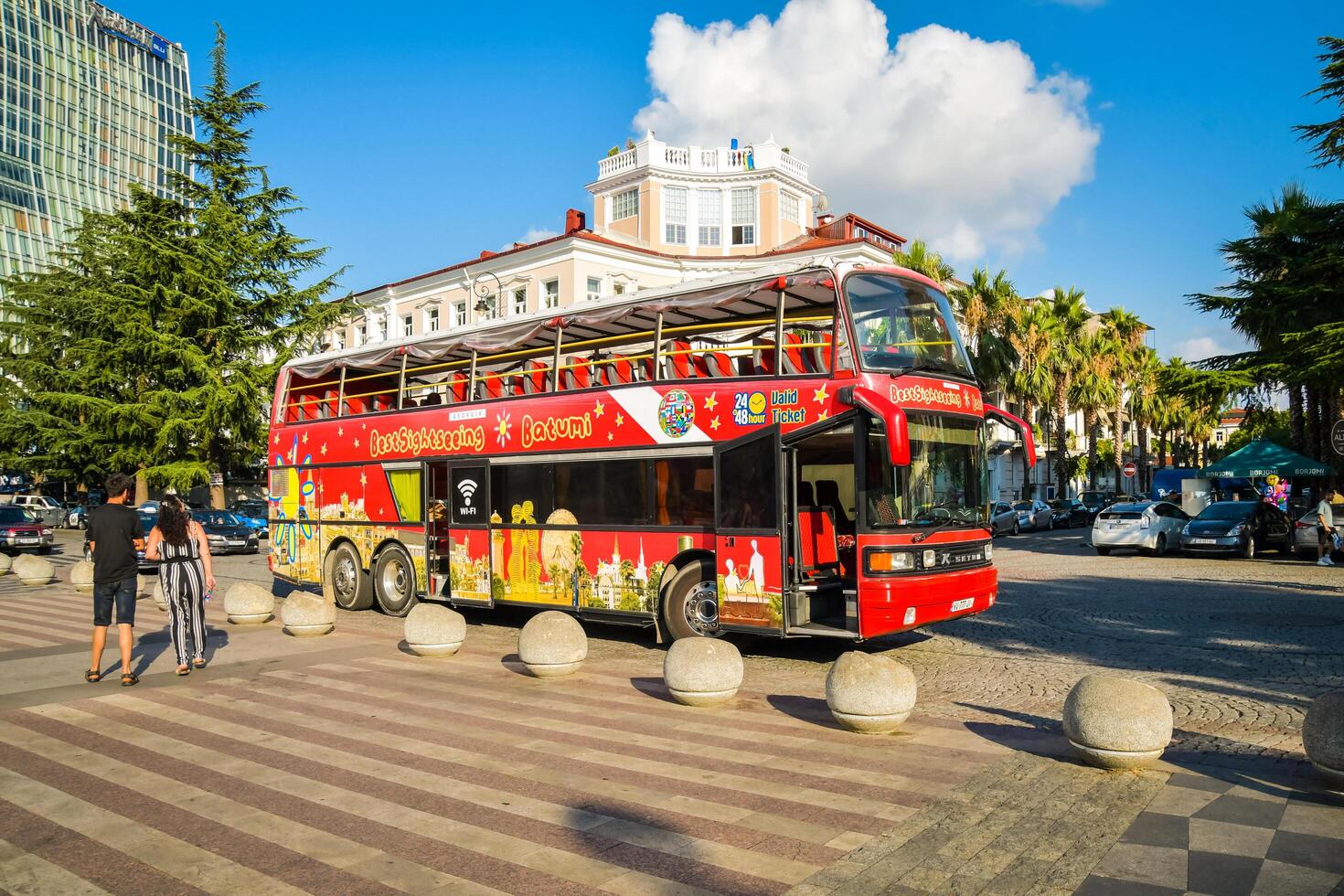 Batumi, Georgia - 4th august, 2022 - female tourist walk us phone in street pass red two floor double-decker classic sightseeing bus around city. Famous city attraction photo