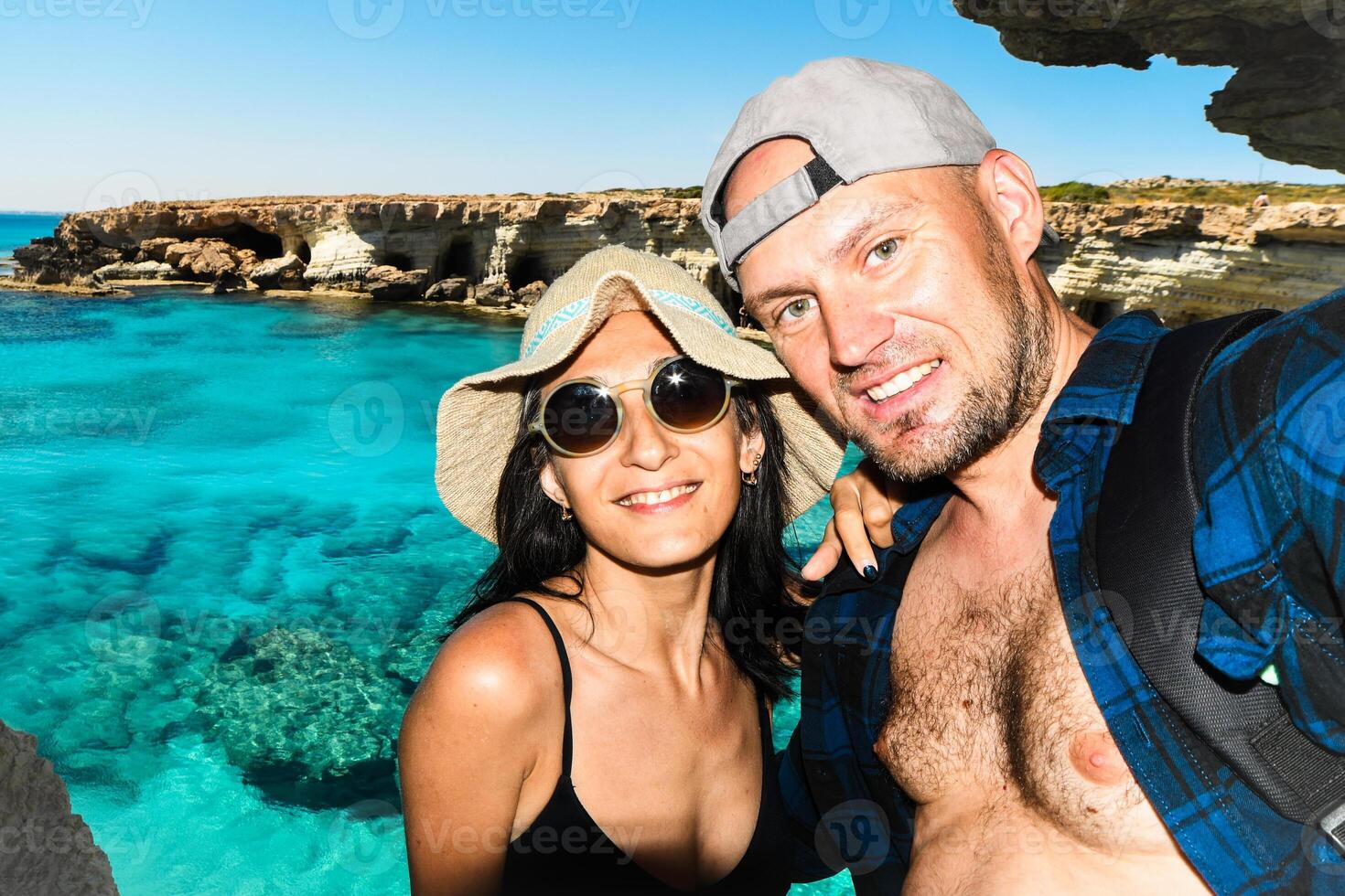 Happy young couple in love takes selfie portrait on the beach in Cyprus. Pretty tourists make funny photos for travel blog in Europe