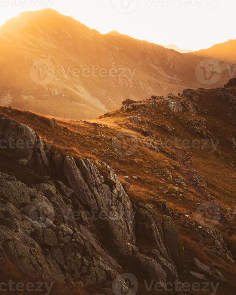 Static tracking view hiker backpacker on black rock trail in Lagodekhi enjoy dramatic sunset over mountain against sun photo