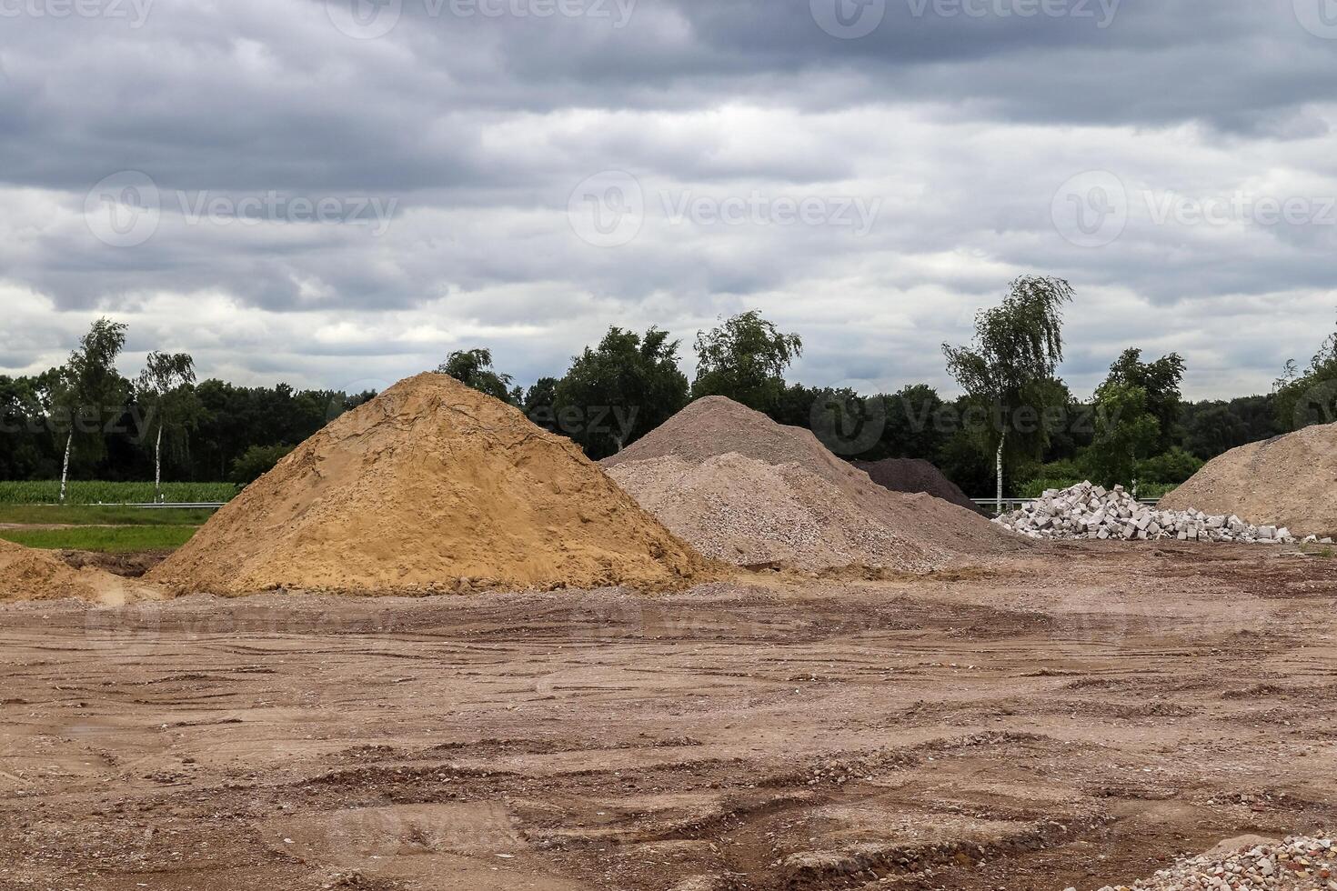 View into a gravel pit with piles of sand and some tire tracks photo