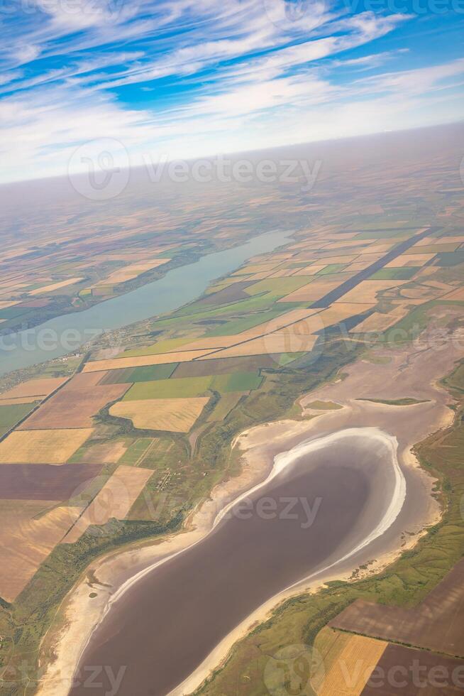 Land view through the airplane window. Fields, roads, rivers from a bird's eye view. Porthole. Look out the window of a flying plane. Top view of the ground photo