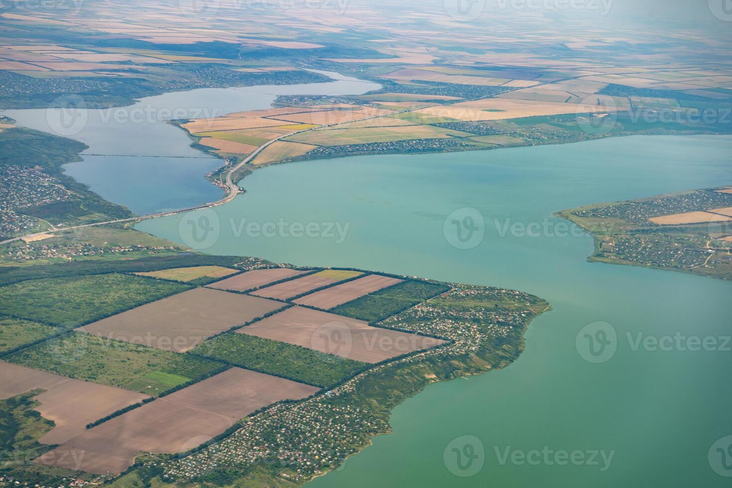 Land view through the airplane window. Fields, roads, rivers from a bird's eye view. Porthole. Look out the window of a flying plane. Top view of the ground photo