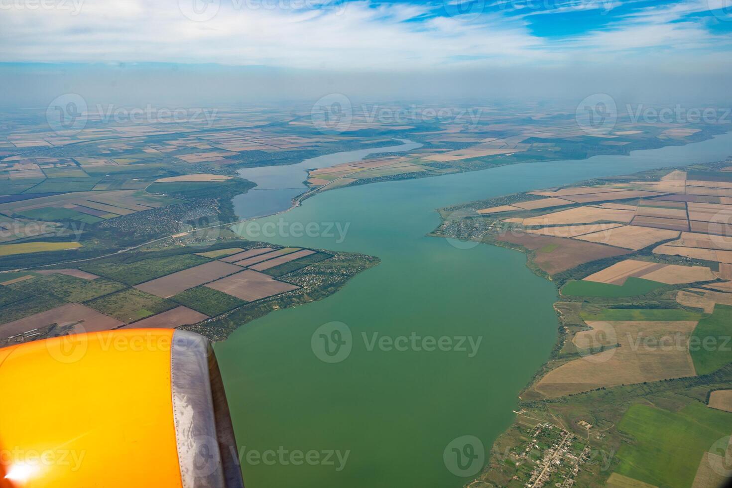 Land view through the airplane window. Fields, roads, rivers from a bird's eye view. Porthole. Look out the window of a flying plane. Top view of the ground photo