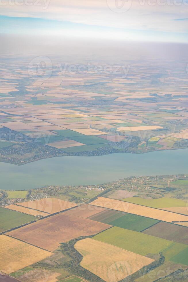Land view through the airplane window. Fields, roads, rivers from a bird's eye view. Porthole. Look out the window of a flying plane. Top view of the ground photo