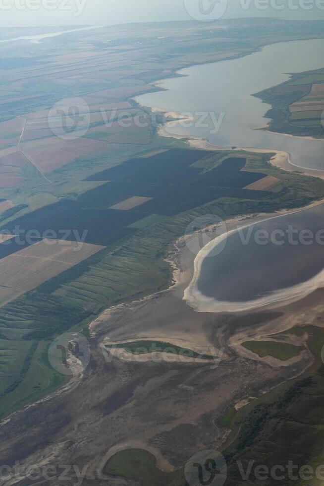 Land view through the airplane window. Fields, roads, rivers from a bird's eye view. Porthole. Look out the window of a flying plane. Top view of the ground photo
