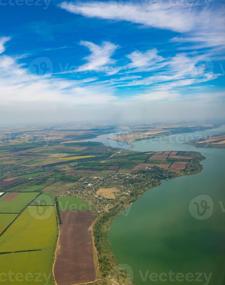 Land view through the airplane window. Fields, roads, rivers from a bird's eye view. Porthole. Look out the window of a flying plane. Top view of the ground photo