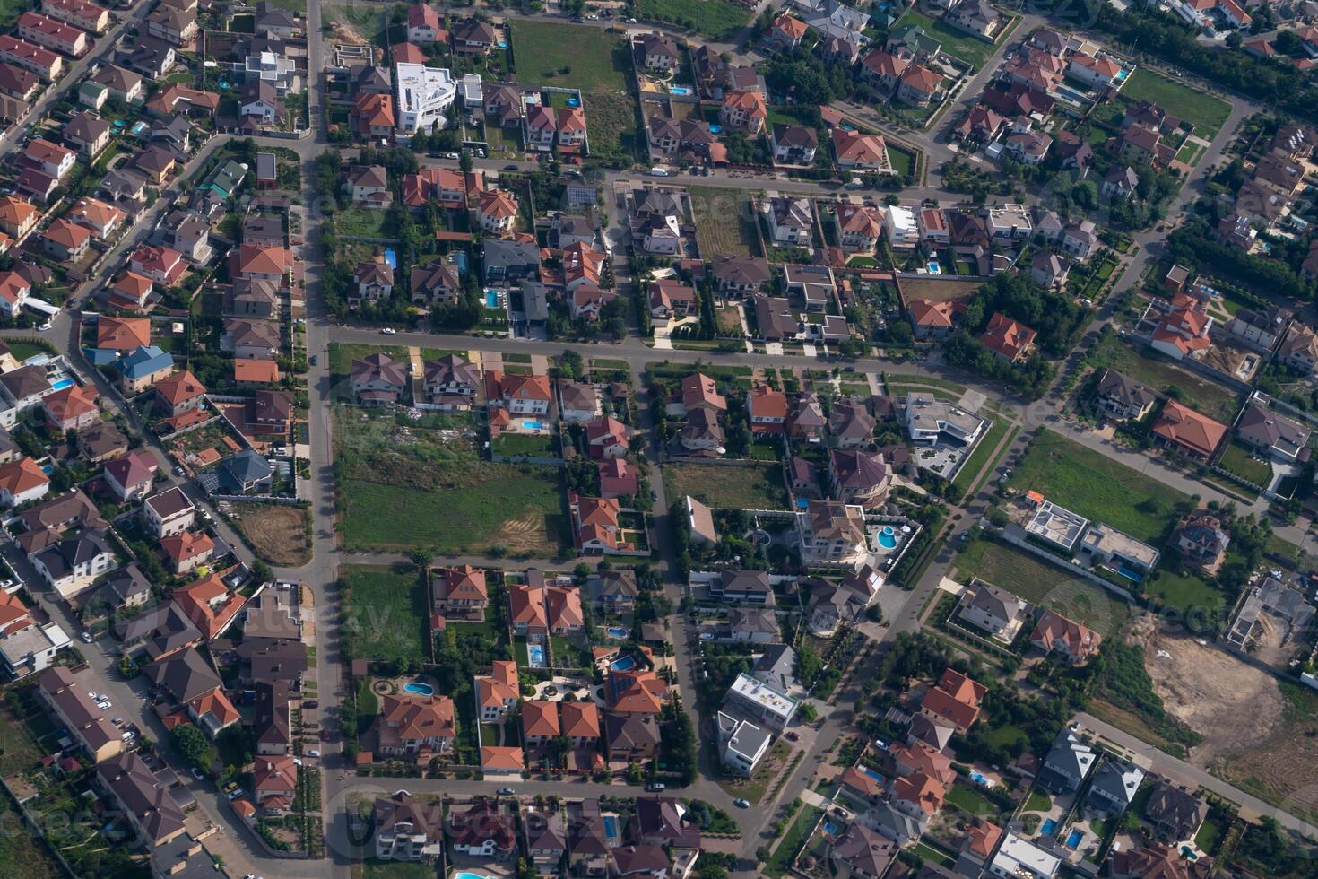 Residential area, rooftops, view from a drone. Cottages in the village. Land view through the airplane window. . Look out the window of a flying plane. Top view of the ground photo